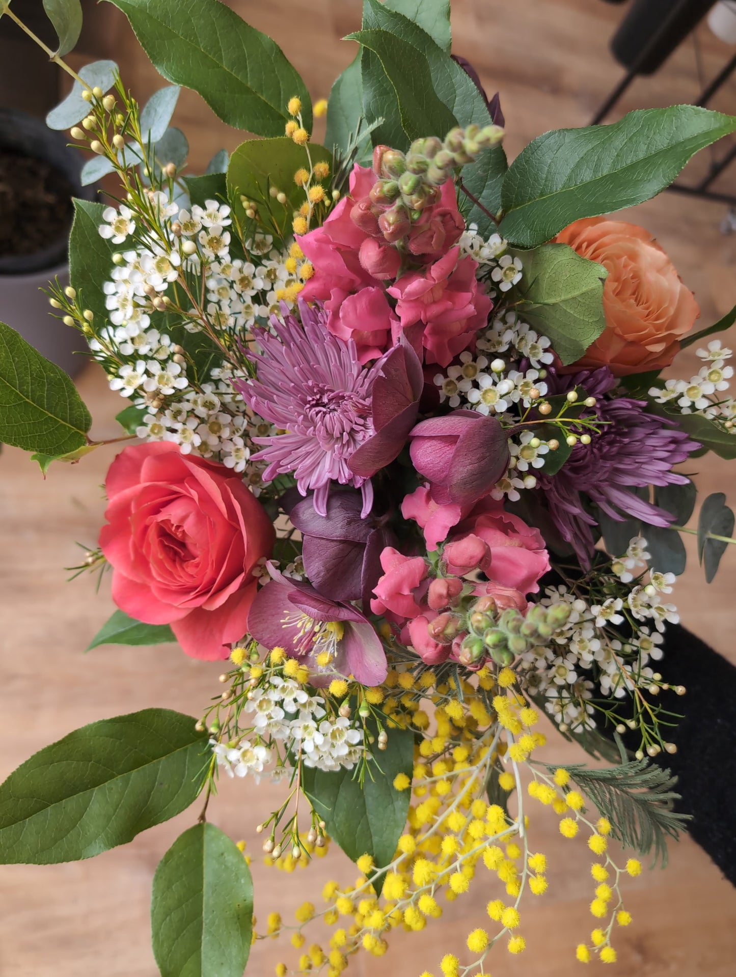 A bouquet of flowers with a variety of colors, prominently featuring yellow mimosa flowers.