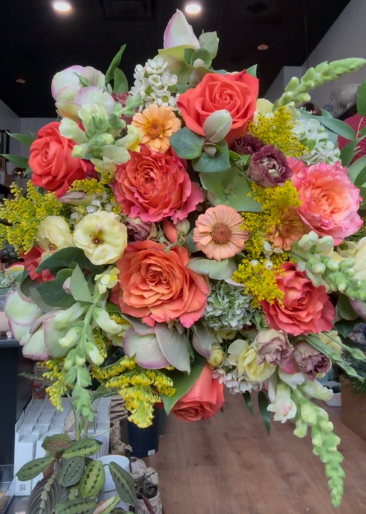 Colorful extra large bouquet with a variety of flowers on a wooden surface.