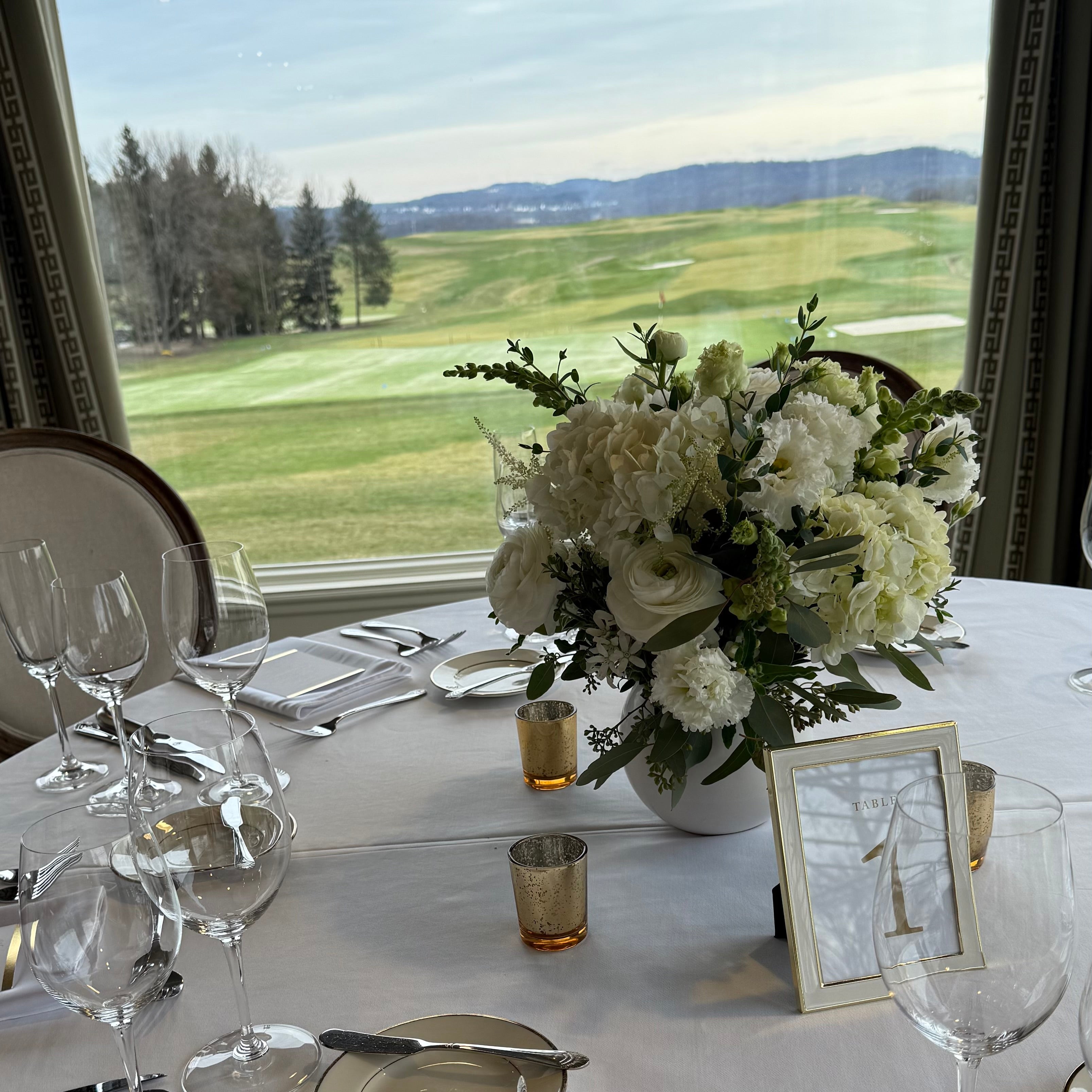 Elegant table setting with floral centerpiece and view of Oakmont Country Club golf course.